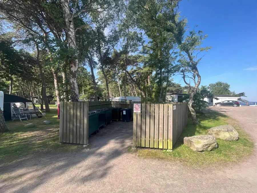 Miljöstation med sopkärl bakom ett staket