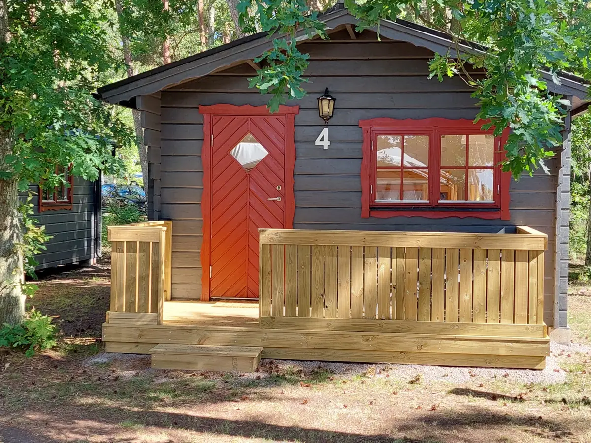 Campingstuga med röd dörr och altan